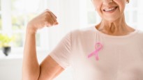 Woman making muscle while wearing a breast health awareness ribbon.
